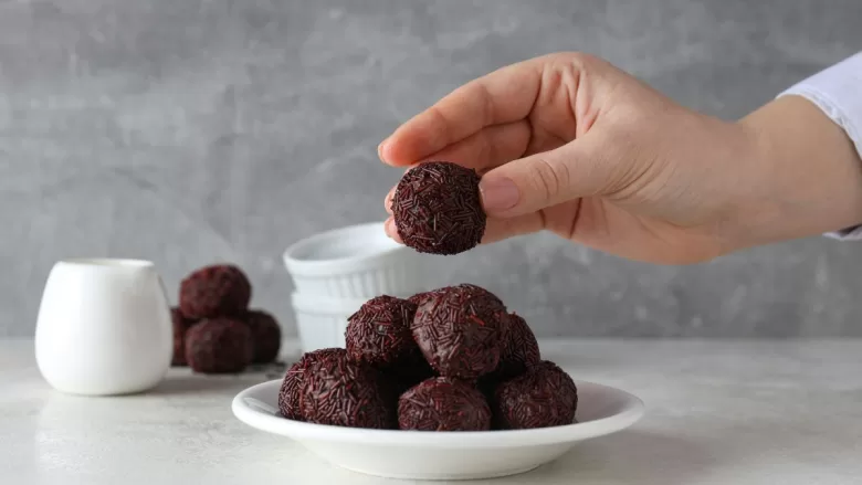 Mulher segurando brigadeiro para vender.